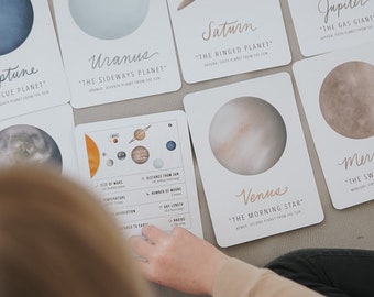May include: A set of colorful illustrated flashcards featuring the planets of our solar system. Each card includes the name of the planet, a description, and a watercolor illustration of the planet. The cards are perfect for learning about space and the planets.
