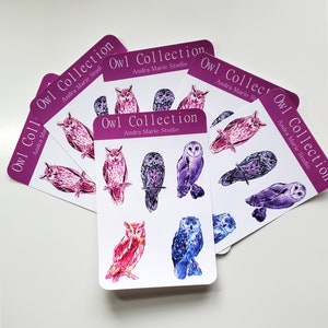 May include: A set of six cards featuring watercolor illustrations of owls. Each card has the text "Owl Collection" and "Andra Marie Studio" printed on it. The owls are depicted in shades of purple, pink, and blue.