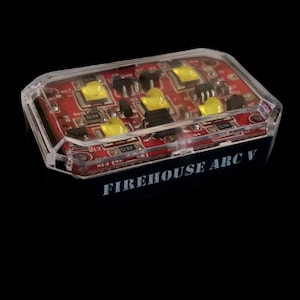 May include: A small, clear plastic case with a red circuit board inside. The case has the text "FIREHOUSE ARC V" printed on the front.