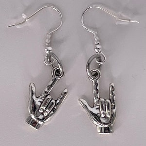 May include: Silver earrings with a hand sign for 'I love you' in American Sign Language.
