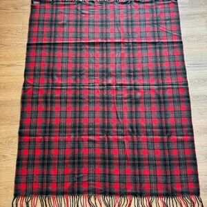 Puede incluir: Una manta rectangular a cuadros rojos, negros y grises, con flecos en los bordes superior e inferior. La manta presenta un patr&oacute;n de tart&aacute;n cl&aacute;sico, adecuado para la decoraci&oacute;n del hogar o para uso en exteriores.