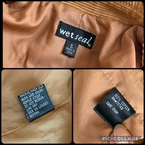 May include: Close-up of the inside of a brown corduroy jacket. The image shows three tags. The first tag reads "wet seal" and "S MADE IN CHINA". The second tag reads "MACHINE WASH COLD WITH LIKE COLOR GENTLE CYCLE DO NOT BLEACH LINE DRY IRON ON LOWEST SETTING". The third tag reads "100% COTTON RN#78749 CARE OVER".