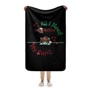 a person holding a black towel with a cat on it
