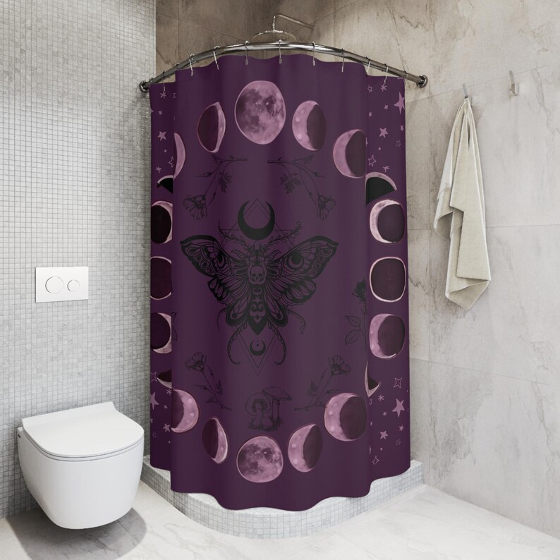 a purple beach towel with a design of the moon and butterfly, along with the text "The moth & moon" printed on it. The towel is placed on a sandy beach, with a straw hat, sunglasses, and flip flops nearby.