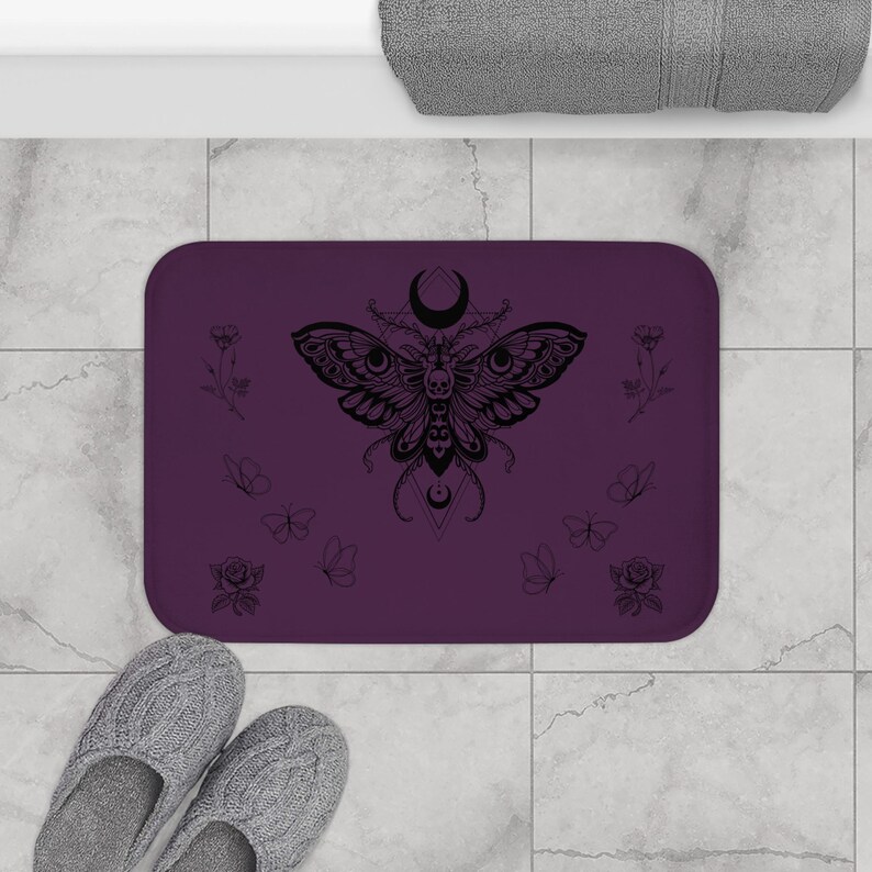 a purple beach towel with a design of the moon and butterfly, surrounded by various beach-related items such as a smartphone, flip flops, and seashells.