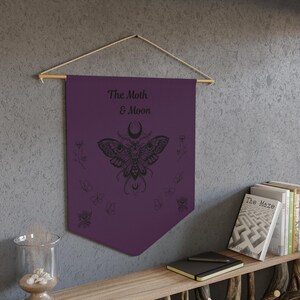 a purple beach towel with a design of the moon and butterfly, surrounded by various beach-related items such as a smartphone, flip flops, and seashells.