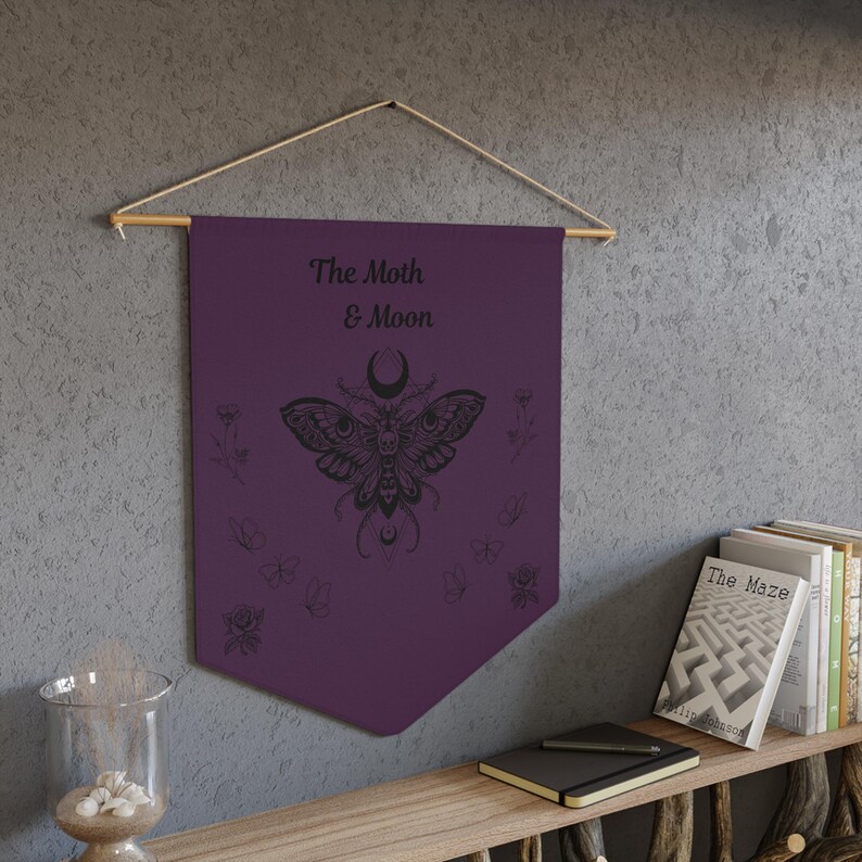 a purple beach towel with a design of the moon and butterfly, surrounded by various beach-related items such as a smartphone, flip flops, and seashells.