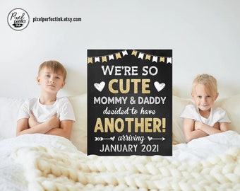 May include: A chalkboard sign with gold glitter accents announcing a pregnancy with the text "We're so cute Mommy & Daddy decided to have another! arriving January 2021". Two children are sitting on a bed with a white knitted blanket.