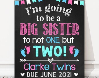 Op de afbeelding: Een zwart schoolbordbord met witte, roze en blauwe tekst met de aankondiging "I'm going to be a BIG SISTER to not ONE, but TWO!" met babyvoetjes en de namen "Clarke Twins" en "DUE JUNE 2021".