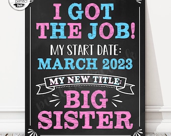 May include: A black chalkboard style sign with the text "I got the job!" in pink and blue. The sign also includes the text "My start date: March 2023" and "My new title: Big Sister" in pink and blue.