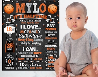 May include: A chalkboard style birthday sign with an orange basketball theme. The sign says "Mylo It's Halftime" and includes details about the child's age, weight, height, favorite foods, and things they can do. A photo of a baby boy is in the background.