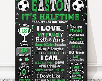 May include: Black chalkboard sign with green and white text and graphics. The sign says "Easton It's Halftime" and includes details about the child's age, weight, height, favorite foods, and personality. The sign is decorated with soccer balls.