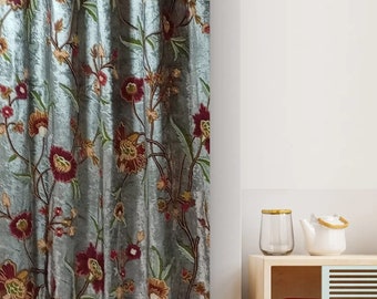 May include: A teal velvet curtain with a floral pattern in shades of red, yellow, and green. The curtain is hanging in a room with a wooden shelf and a glass vase.