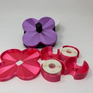 Pode incluir: Um conjunto de organizadores de secret&aacute;ria em forma de trevo, em tons de rosa e roxo. O conjunto inclui uma bandeja, um dispensador de fita adesiva com dois rolos e um porta-canetas. Os artigos s&atilde;o feitos de pl&aacute;stico.