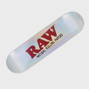 May include: A skateboard deck with a holographic finish. The word "RAW" is printed in red, along with "NATURAL ROLLING PAPERS" in black. The deck is designed for skateboarding.