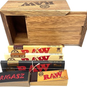 May include: A wooden box with a sliding lid, containing various packs of RAW rolling papers. The packs include Classic, Organic Hemp, Black, and King Size Slim. The box also includes a pack of RAW tips.