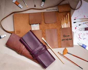 May include: A brown leather roll-up case with multiple compartments for holding paint brushes. The case has a strap and is rolled up with a leather tie. The case is open and shows a variety of paint brushes inside. The case has the text "You are your only limit" printed on the front. There are two additional brown and purple leather cases with straps.