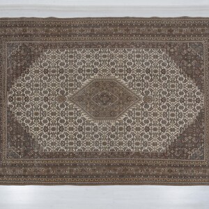 May include: Rectangular area rug with a central diamond design and an intricate floral pattern in shades of brown and beige. The rug has a detailed border and a traditional aesthetic, suitable for home decor.