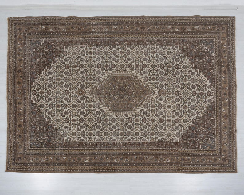 May include: Rectangular area rug with a central diamond design and an intricate floral pattern in shades of brown and beige. The rug has a detailed border and a traditional aesthetic, suitable for home decor.