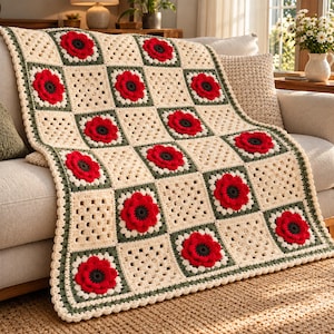 May include: A crochet blanket featuring a repeating pattern of cream-colored granny squares and squares with three-dimensional red poppy flowers. Each floral square is framed by a dark green border, and the entire blanket has a scalloped edge.