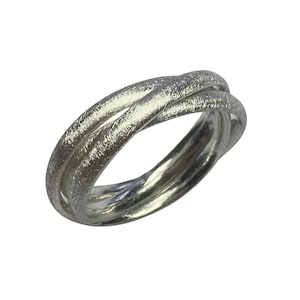 Könnte beinhalten: Ein silberner Ring mit strukturierter Oberfläche, der ein einzigartiges, ineinandergreifendes Design aufweist. Der Ring besteht aus drei Bändern, die miteinander verdreht sind, um eine durchgehende Schleife zu bilden.
