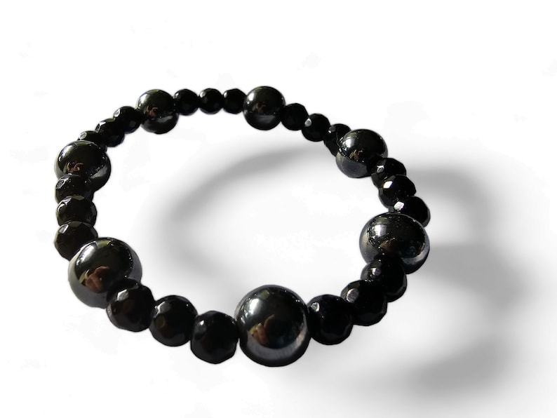 Op de afbeelding: Een zwarte kralen armband met afwisselend grote en kleine kralen. De grote kralen zijn rond en glad, terwijl de kleine kralen gefacetteerd zijn.