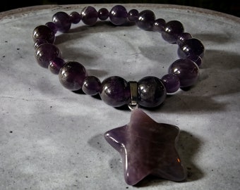 May include: A purple amethyst gemstone bracelet with a star-shaped pendant. The bracelet is made of round beads and has a silver clasp.