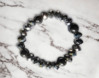 Puede incluir: Un brazalete plateado con cuentas facetadas y cuentas redondas plateadas.