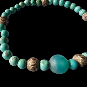 May include: Turquoise beaded bracelet with silver accents. The bracelet features a large turquoise bead in the center.