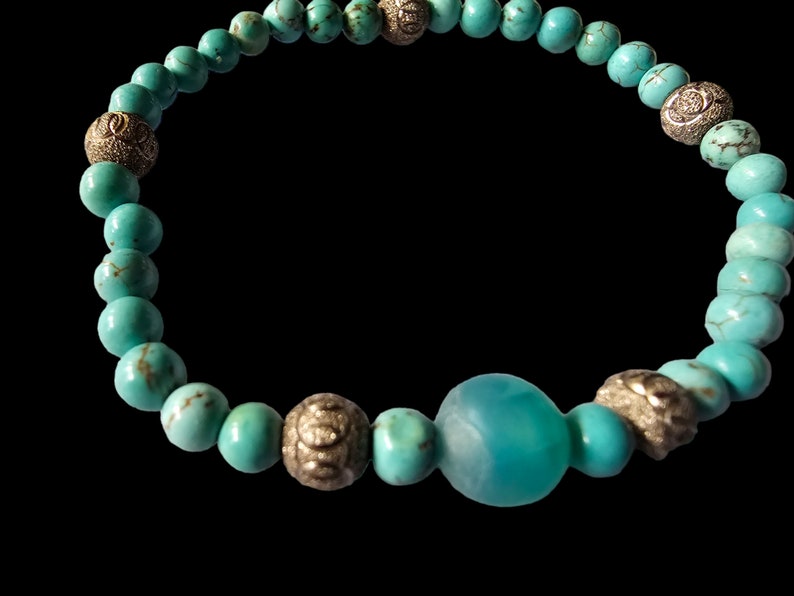 May include: Turquoise beaded bracelet with silver accents. The bracelet features a large turquoise bead in the center.