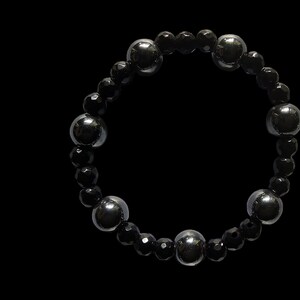 Op de afbeelding: Een zwarte kralen armband met afwisselende zwarte en zilveren ronde kralen.
