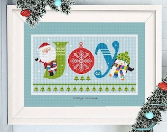 May include: A cross-stitch pattern featuring the word "JOY" with a Santa Claus, a penguin, and a red ornament with a snowflake. The pattern is framed in a white frame and has a blue background.