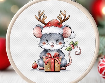 Op de afbeelding: Een grijze muis met een rode en witte kerstmanmuts met rendiergewei houdt een ingepakt cadeau vast met een rode strik. De muis houdt het cadeau vast in zijn voorpootjes en heeft een gelukkige uitdrukking op zijn gezicht.