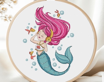 May include: A cross-stitch pattern of a mermaid with pink hair listening to music with headphones. She is surrounded by bubbles and orange fish.