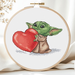 Può includere: Un personaggio dei cartoni animati verde e marrone che tiene un cuore rosso. Il personaggio ha grandi orecchie e grandi occhi. Il cuore ha la forma di un cuore tradizionale di San Valentino.