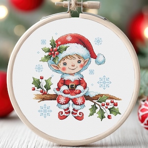 Peut inclure: Un adorable lutin de Noël portant un chapeau et un costume rouge et blanc est assis sur une branche avec des baies de houx. Le lutin a une barbe blanche et sourit. L'arrière-plan est blanc avec des flocons de neige.