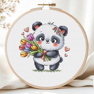 Puede incluir: Un panda blanco y negro sosteniendo un ramo de tulipanes coloridos. El panda lleva una corona de flores y hay corazones en el fondo.