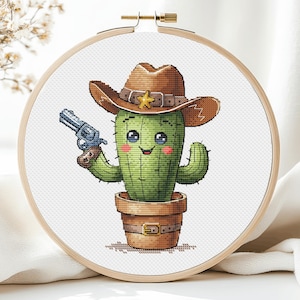 May include: A green cactus wearing a brown cowboy hat with a gold star and holding a silver toy gun. The cactus is in a brown pot with a brown belt around it.