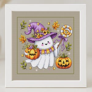 Puede incluir: Diseño de punto de cruz enmarcado con un fantasma amistoso con un sombrero de bruja morado adornado con flores. El fantasma sostiene una calabaza y una piruleta. Hojas de otoño y calabazas completan el tema de Halloween.