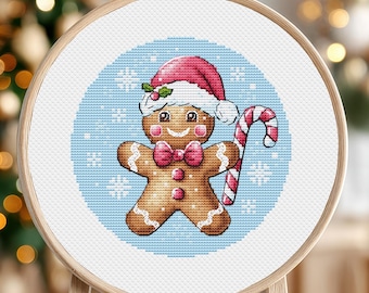May include: A gingerbread man wearing a pink and white Santa hat holds a candy cane in front of a blue background with white snowflakes.