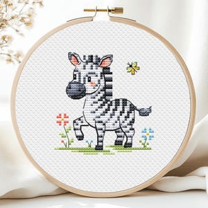 May include: A cross-stitch embroidery hoop featuring a cartoon zebra with black and white stripes, standing on green grass with colorful flowers. A yellow butterfly is also included in the design. The hoop is made of wood.
