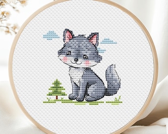 May include: A cross-stitch embroidery in a wooden hoop features a cartoon wolf with gray fur, pink ears, and rosy cheeks. The wolf sits on green grass with a small tree and blue cloud accents. The embroidery is on white fabric.