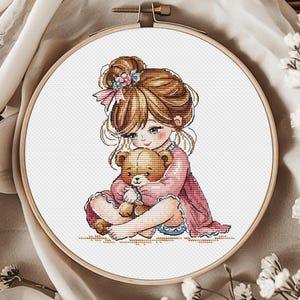 May include: A cross-stitch pattern featuring a young girl with brown hair and a pink dress holding a brown teddy bear.