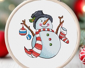 May include: A white snowman with a black hat, red and white striped scarf, and a carrot nose. The snowman is holding a blue and red ornament and a red and white stocking.