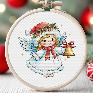 May include: A white angel with a red and green holly wreath on her head, holding a gold bell. She is wearing a white robe with a red scarf and has blonde hair. The angel is surrounded by a white background with gold stars.