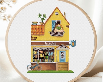 May include: A yellow building with a sign that says "BOOKS" and a window with a person reading a book. The building has a balcony with a potted plant and a bicycle in front of it.