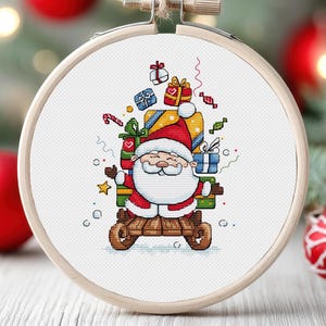 May include: A cross-stitch pattern featuring a cartoon Santa Claus riding a sleigh with a pile of colourful presents. The pattern is framed in a wooden hoop.