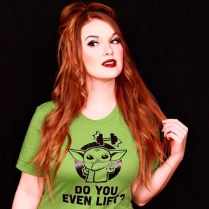 K&ouml;nnte beinhalten: Hellgr&uuml;nes T-Shirt mit einer Cartoon-Figur und dem Text "DO YOU EVEN LIFT?". Die Grafik zeigt eine Hantel und die Figur zeigt das Friedenszeichen.