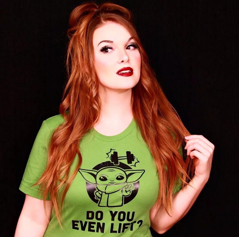 K&ouml;nnte beinhalten: Hellgr&uuml;nes T-Shirt mit einer Cartoon-Figur und dem Text "DO YOU EVEN LIFT?". Die Grafik zeigt eine Hantel und die Figur zeigt das Friedenszeichen.