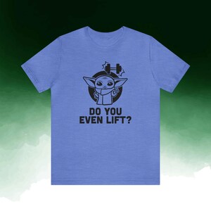 K&ouml;nnte beinhalten: Hellblaues T-Shirt mit einer schwarzen Grafik eines Zeichentrickcharakters und dem Text "DO YOU EVEN LIFT?". Die Figur befindet sich in einem schwarzen Kreis mit einer Hantel &uuml;ber dem Kopf.